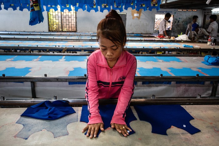 Phnom Penh, Cambodia, 3 april 2015, this garment worker prepares shirts and puts them on a long row for making prints on them, while the smell of dying penetrates the nose,  at a subcontractor with no name on the front door.  A high number of not registered garment  factories, operating in a legal vacuum, fulfill orders from registered factories. This picture was shot because the manager let us in, but we had to flee when the boss was comming, as illegal factory owners don't want any journalists around.